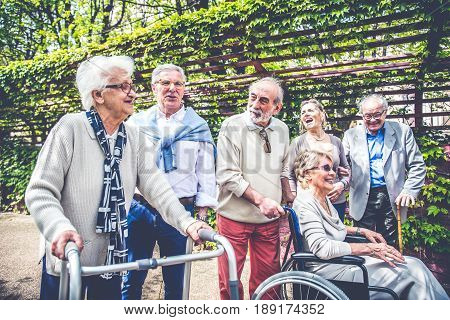 Group of senior people with some diseases walking outdoors - Mature group of friends spending time together