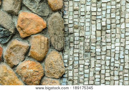 The junction of a cobblestone wall and a shallow mosaic. Wall with various finishes with natural stone. Mixed finishing wall