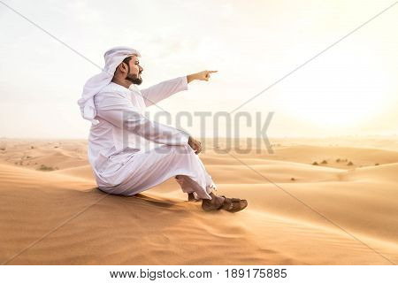 Arabian man walking in the desert at sunrise