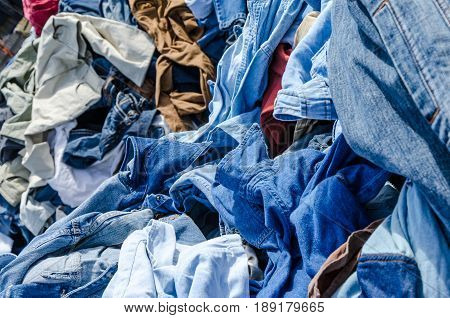 Heaps of clothing on the second hand market. Pile of second hand clothes at a garage sales