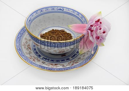 one pink flower fuchsia and black instant coffee in a small Cup and saucer