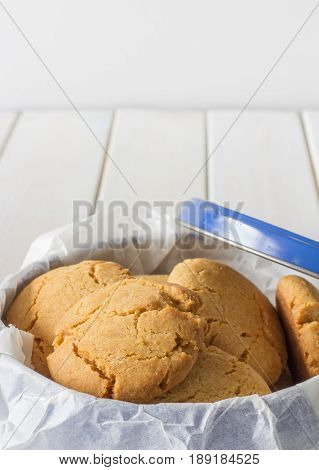 Close Up of Homemade Gingernuts in a Blue Tin on White Wooden Table Vertical with Copy Space Above