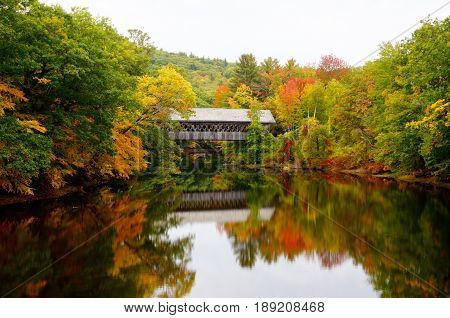 Covered bridge in the heart of New Hampshire during the fall with reflections from the river below