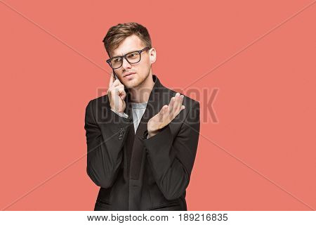 The young caucasian businessman in glasses on red studio background talking on cell phone