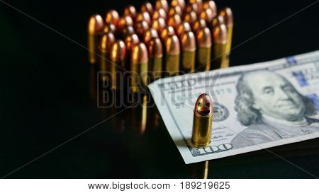 9mm bullet and US 100 dollars on the black mirror background.