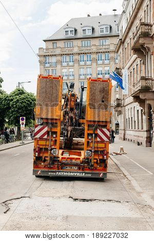 STRASBOURG FRANCE - MAY 18 2016: Rear view of Mercedes-Benz Actros 2660 truck transporting construction excavator at the construction site in urban environment during roadwork - truck excavator transport