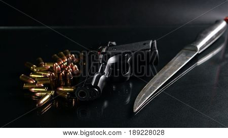 Black hand gun and bullets on the black mirror background.