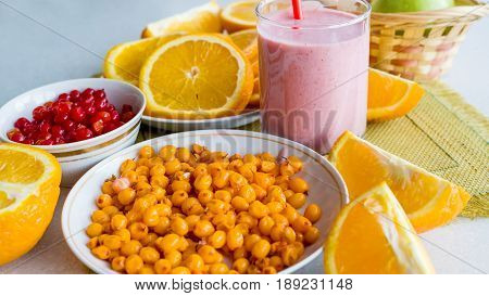 Orange sea-buckthorn berries, cranberries, orange slices and strawberry smoothies on the dining table