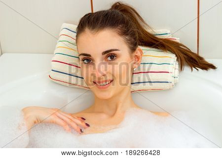 Portrait of smiling cute Brunettes that lies in the bath with foam close-up