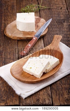Sliced fresh brined white cheese from cow milk on wooden table