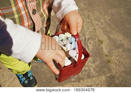 Children's hands and colorful chalk on a playground