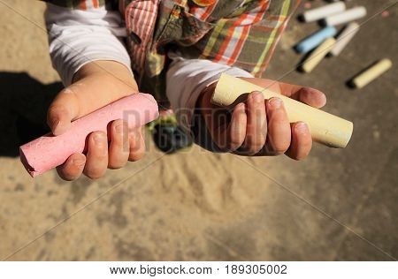 Children's hands and colorful chalk on a playground