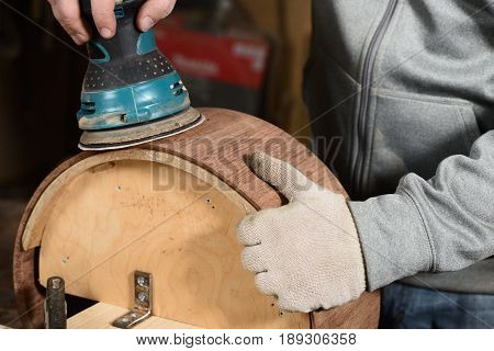 Carpenter grinding handmade wooden drum with sandpaper closeup