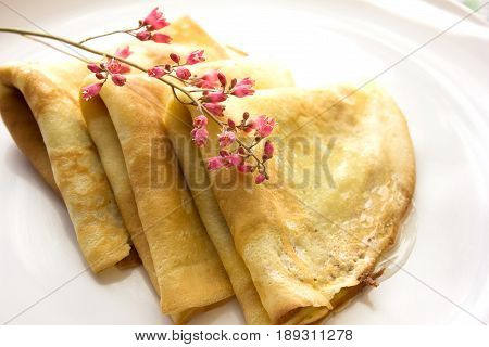 Stack of thin crepes for breakfast on white plate