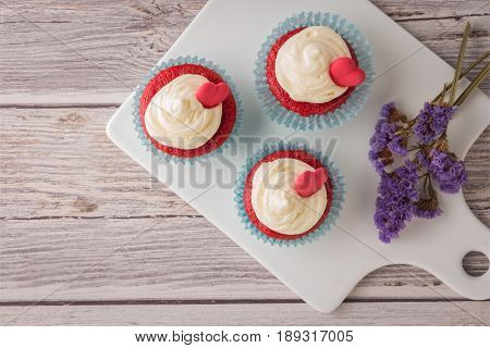 Red velvet heart cupcakes with cream cheese frosting and a red heart for Valentine's Day. Top view with copy space