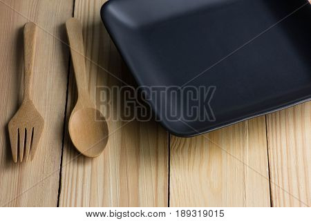 Ceramic black plate and spoon on the wooden table