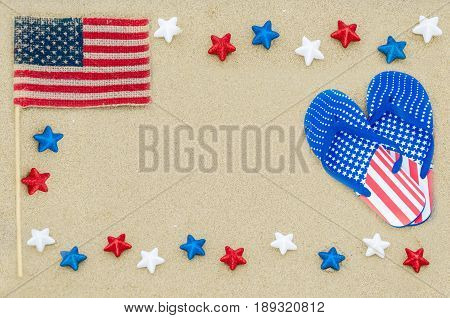 Patriotic USA background with flip flops and American flag on the sandy beach