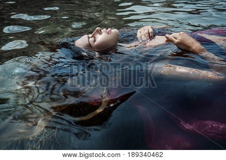 beautiful young woman in red dress laying dowm in water