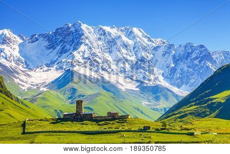 View on Ushguli village at the foot of snow-capped Mt. Shkhara. Location place Lamaria Church Jgrag Upper Svaneti Georgia Europe.
