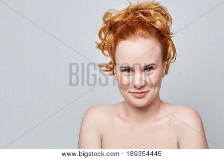 Human face expressions emotions and feelings. Closeup studio portrait of beautiful young cheerful Caucasian redhead freckled woman smiling playfully at the camera on grey background wall with copy advertising space.