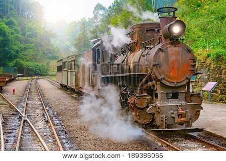 Steam narrow-gauge train with local people stands at the station on the way from Bagou to Yuejin. Mifenguan. Jiayang Mining Region. Sichuan province. China.