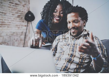 Happy african american couple relaxing together on the sofa.Young black man and girl using modern laptop for video conversation with friends.Horizontal, blurred background