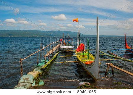 Several Traditional Filipino Outrigger Boats Or 'banca' Moored At A Wooden Pier On The Shore Of Taal