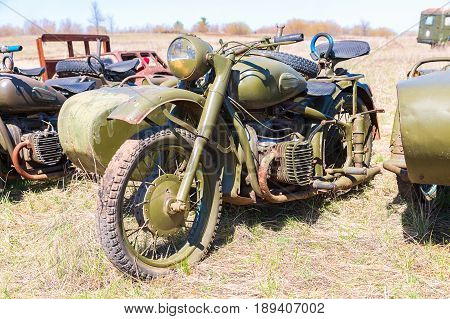 Samara Russia - April 30 2017: Russian vintage rusty motorcircle at the field in sunny day. Soviet military retro motorcycle