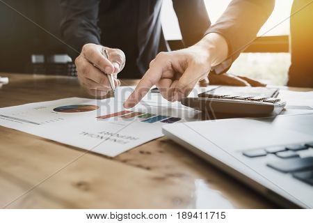 Young business man pointing graph chart with pathner for analyze plans in this mounth. vintage tone.