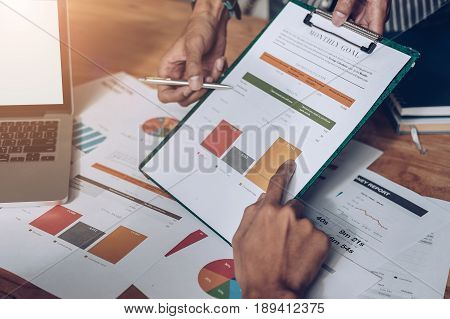 Businessman pointing graph chart with pathner for analyze plans in this mounth. vintage tone.