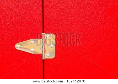 Construction details silver objects concept. Closeup of metal steel hinge on red door