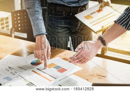 Businessman pointing graph chart with pathner for analyze plans in this mounth. vintage tone.