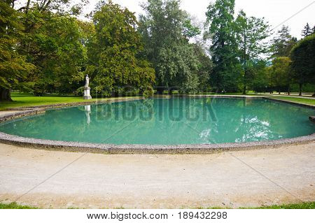 Big pond with azure water in the park of the palace Hellbrunn in Salzburg Austria. Artificial reservoir in the territory of the estate