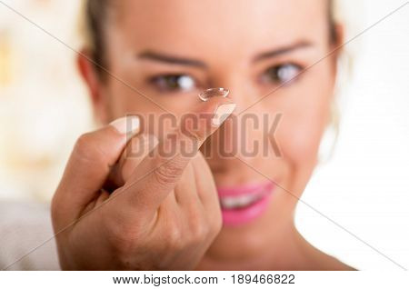 Young woman holding contact lens on finger in front of her face on white background., eyesight and eyecare concept.