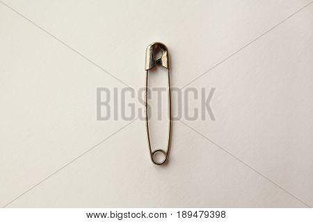 old rusty closed safety pin on white paper background. minimal style. close-up macro view.