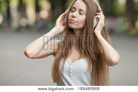 Pretty girl listening music with her headphones in the street