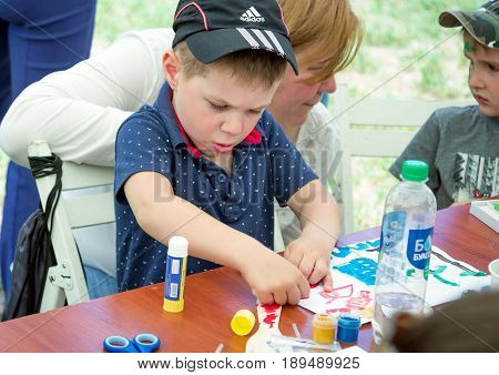 Zaporizhia/Ukraine- May 28, 2017: Charity Family festival:  art and craft activity, boy cocentrated on work at drawing workshop outdoors