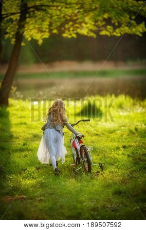 The girl in the lace dress got lost and wandered into the wet dirty grass. Splashes of dirt fly on a bicycle and a dress