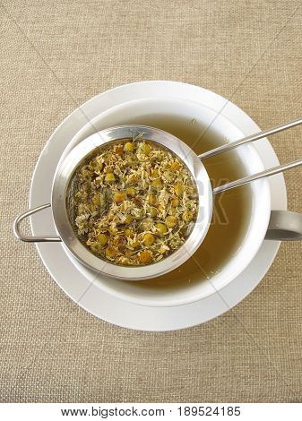 Loose chamomile flowers tea in tea strainer