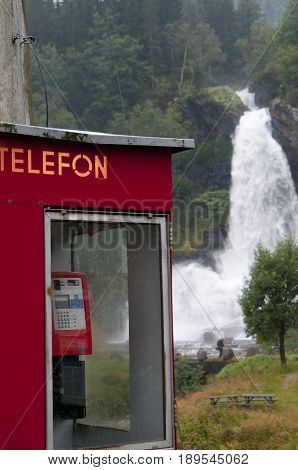 Waterfall And Red Telephonebox In Green And Beautiful Nature.