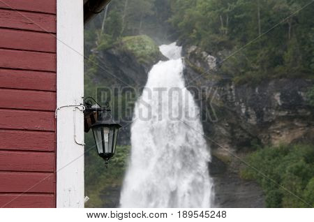 Waterfall and red house in green and beautiful nature.