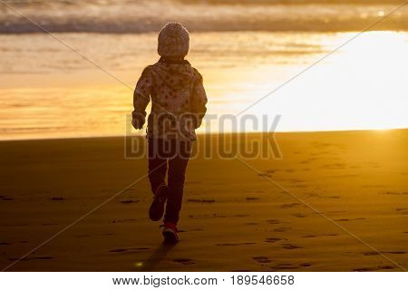 outdoor portrait of young happy smiling child girl in knitted hat on outdoor natural background