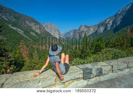 Traveler woman looking panorama at a scenic overlook in Yosemite National Park, California, USA. El Capitan, Half Dome and Bridalveil Fall from the iconic Tunnel View. American Holidays on the Road.