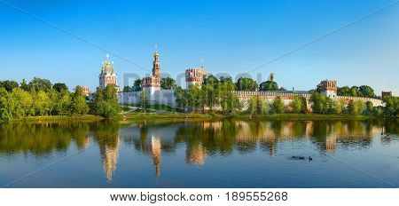 View on cloister monastery chapel walls, bell towers, pond with ducks. City park garden. Novodevichy Convent. Castle style monastery heritage legacy Famous tourist sightseeing holidays vacations tours