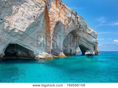 Beautiful view on rock arces arches of Blue caves and travel sightseeing boat with tourists in blue water of Greece islands. Famous Greece holidays vacations sightseeing tours