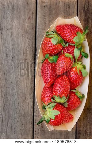 Ripe organic strawberries in birchbark bowl on dark wood background top view summer healthy food clean eating concept top view copyspace
