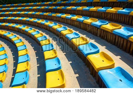 Perspective diagonal curve abstract view on amphitheater theater blue yellow plastic seats. Seats circle. Amphitheater seats architecture background. Diagonal curve. Abstract fractal color background