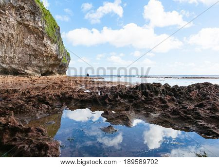 Niue, South Pacific - May 25, 2017;  Mother and son exploring rock pools in distance on coral shelf on tropical Niue