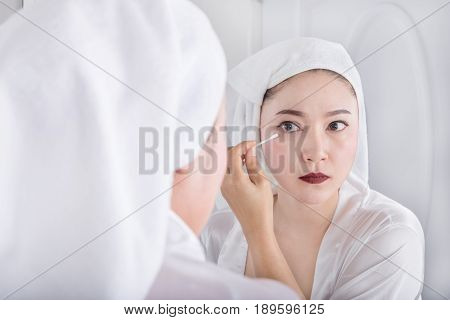 Woman Looking Mirror And Remove Makeup Beside Eye With A Cotton Swab