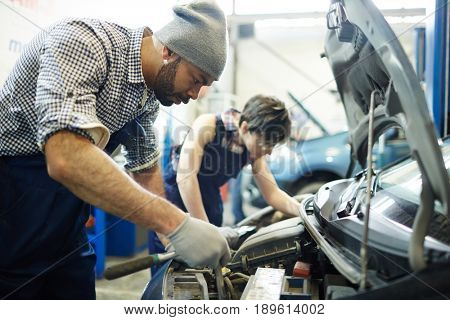 Car service technician repairing engine